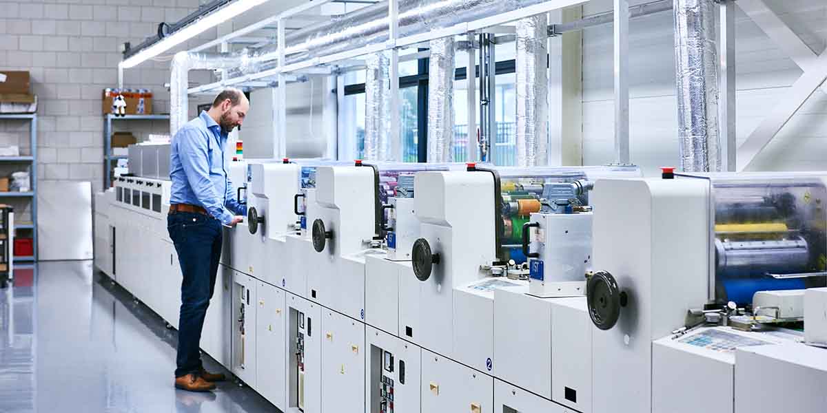 Medewerker met witte handschoenen inspecteert nauwkeurig een roze plastic kaart met een loep, om de kwaliteit te controleren.