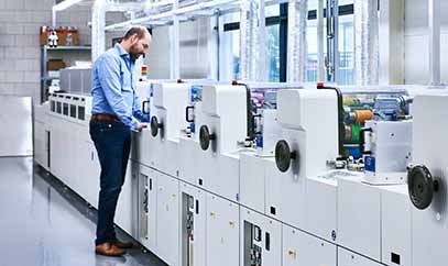 DCP drukkerij en productiefaciliteit Productieruimte van DCP met medewerkers en geavanceerde druk- en verwerkingsmachines voor plastic passen en labels.